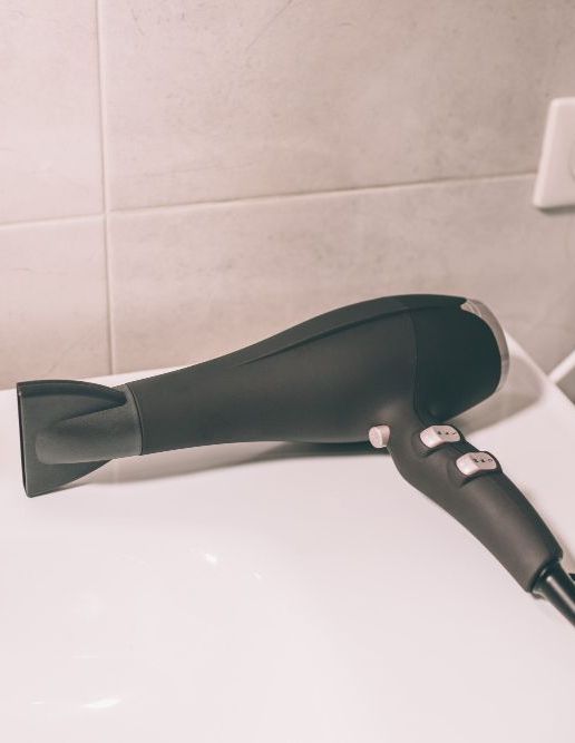 Um secador de cabelo preto está sobre um balcão branco.-Pousada-Casa-Flor