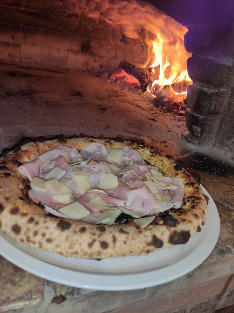 Una pizza è seduta su un piatto bianco davanti a un forno.