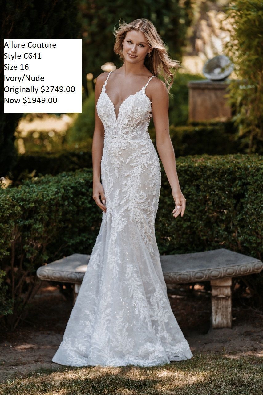 A woman in a white wedding dress is standing next to a stone bench.