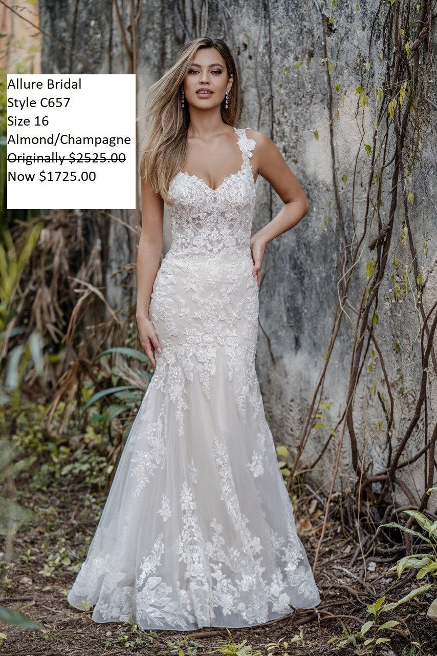A woman in a white wedding dress is standing in front of a wall.
