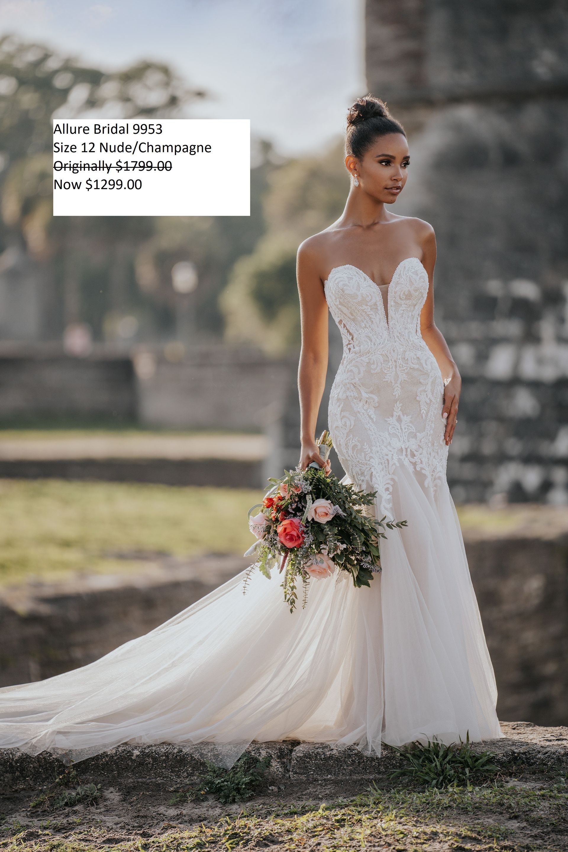 A woman in a wedding dress is holding a bouquet of flowers. Allure Bridal 9953