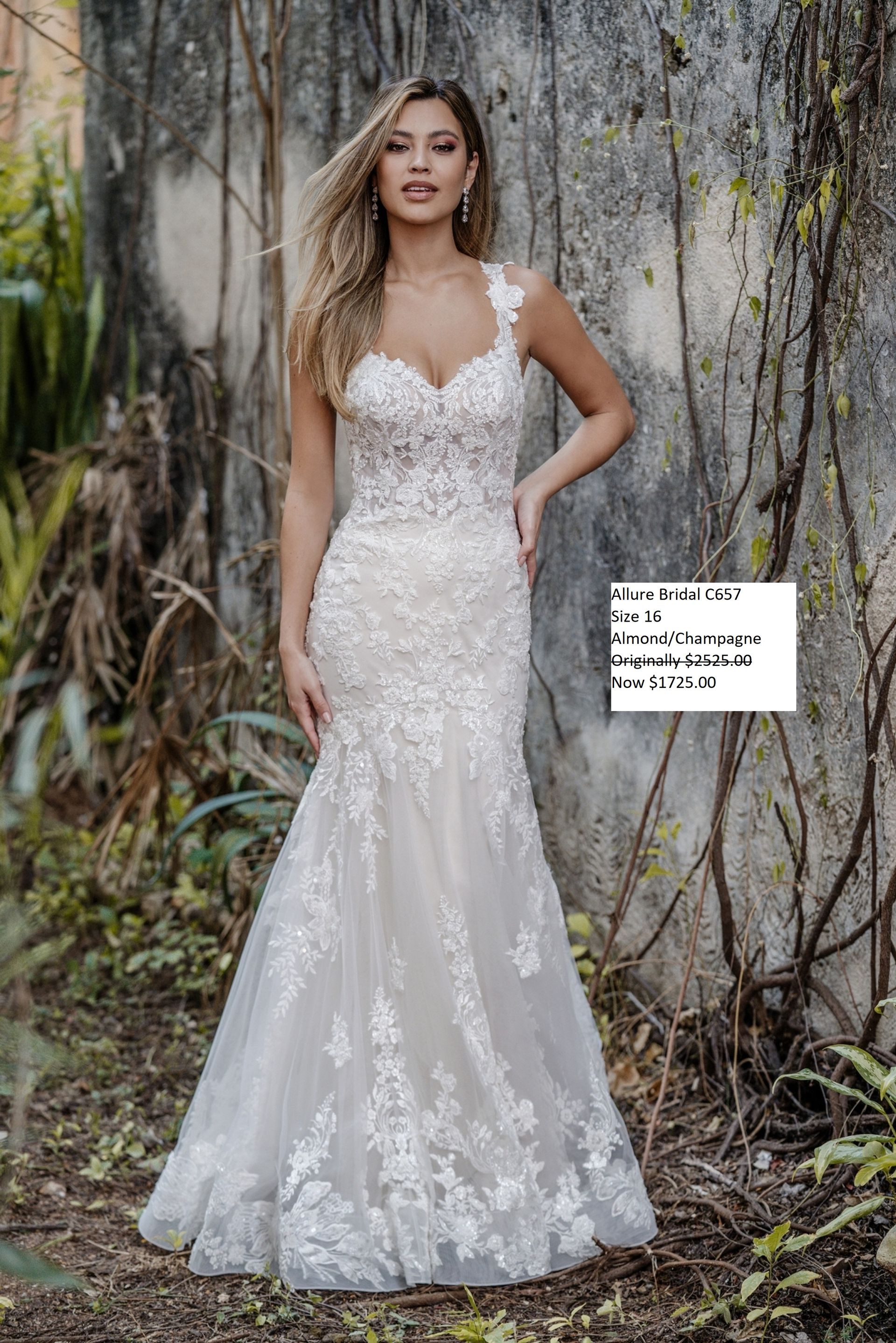 A woman in a white wedding dress is standing in front of a wall. Allure Bridal C657