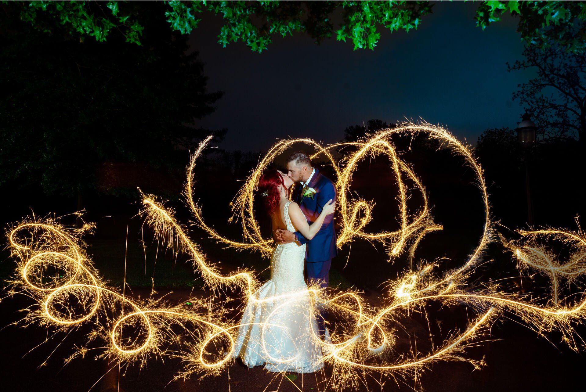 A bride and groom are posing for a picture with sparklers.