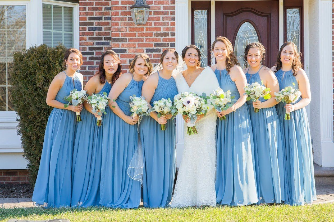 A bride and her bridesmaids are posing for a picture in front of a brick house.