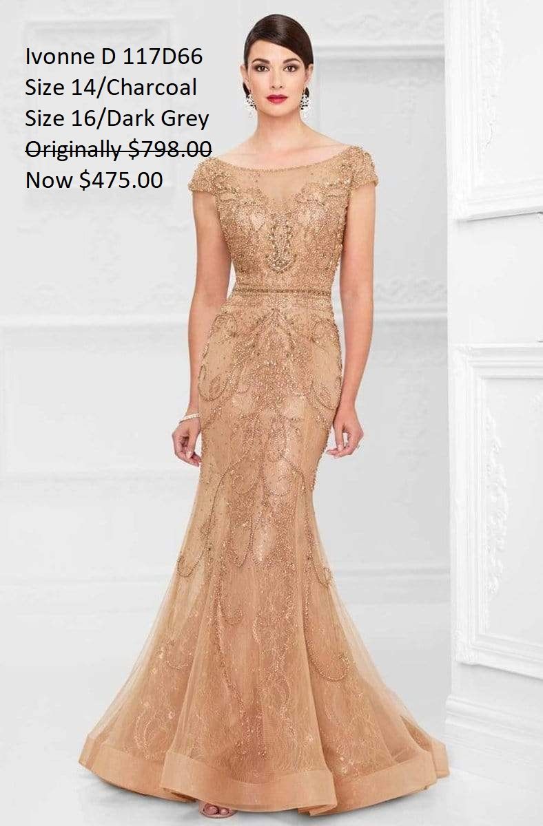 A woman in a long gold dress is standing in front of a white wall.