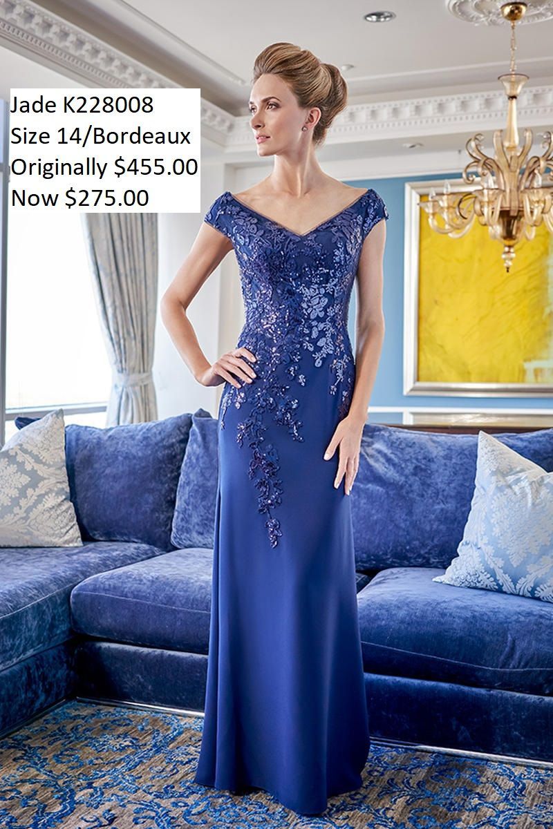 A woman in a blue dress is standing in front of a blue couch.