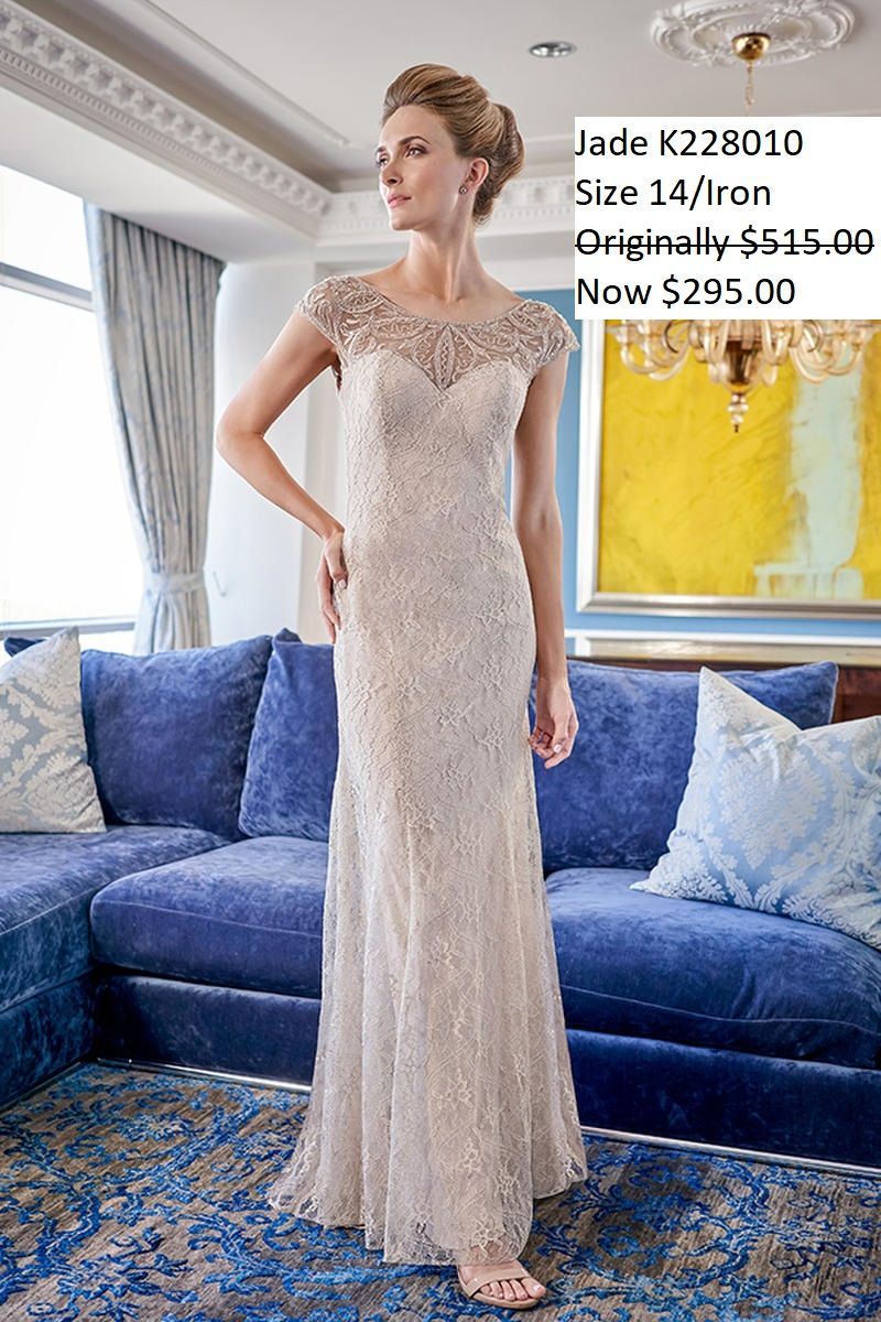 A woman in a long white dress is standing in front of a blue couch.