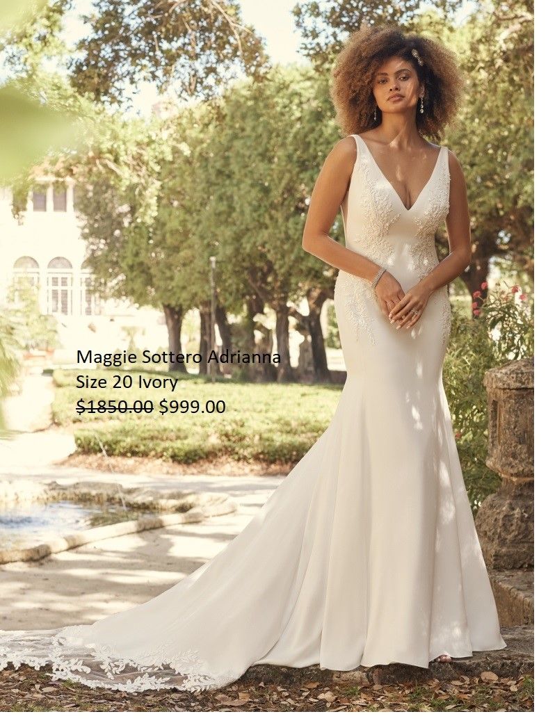 A woman in a white wedding dress is standing in a park.