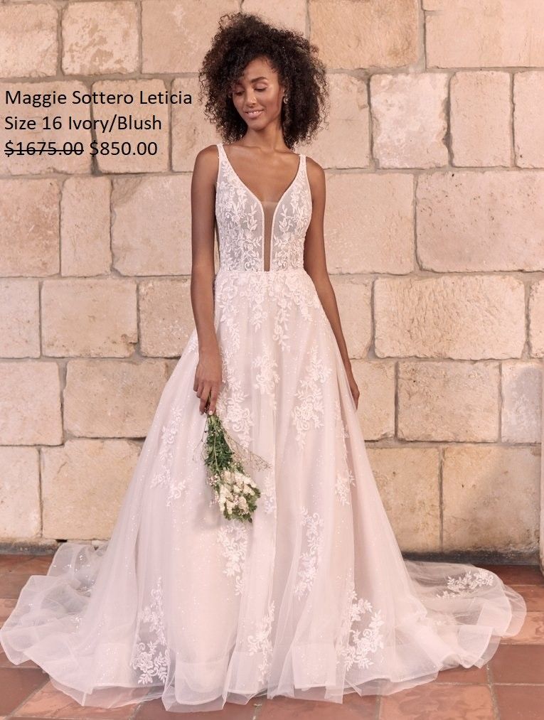A woman in a wedding dress is standing in front of a brick wall holding a bouquet of flowers.