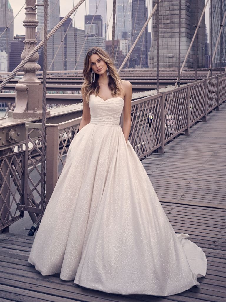 A woman in a wedding dress is standing on a bridge.