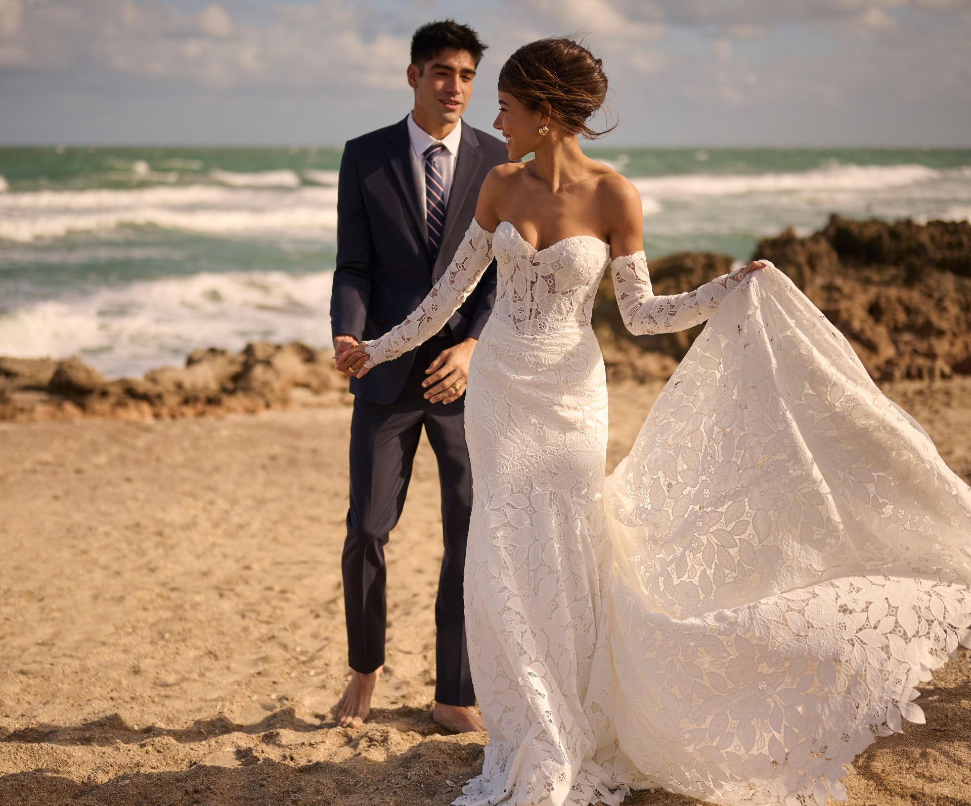 Bride and groom on a beach, woman in white wedding dress, man in suit.