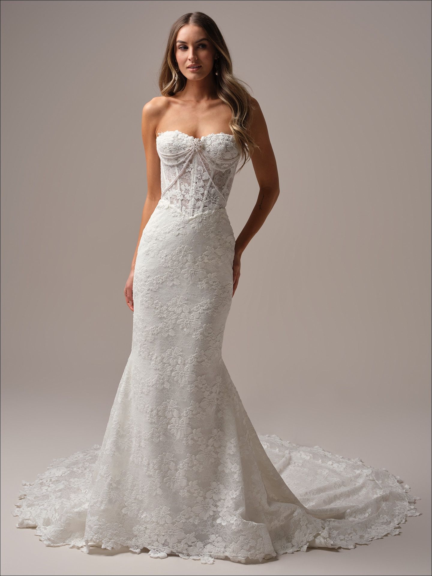 Woman in strapless white lace mermaid wedding dress with long train.