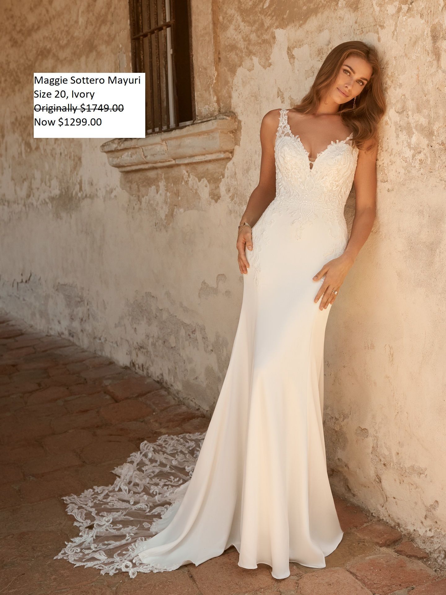 A woman in a white wedding dress is standing in front of a building.