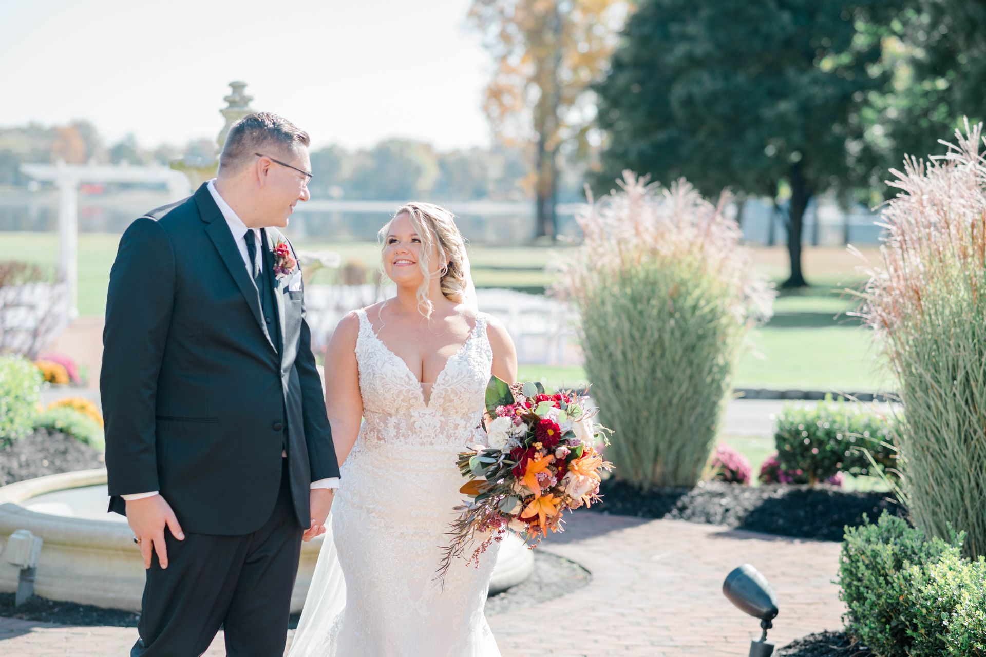 A bride and groom are holding hands and walking in a park.