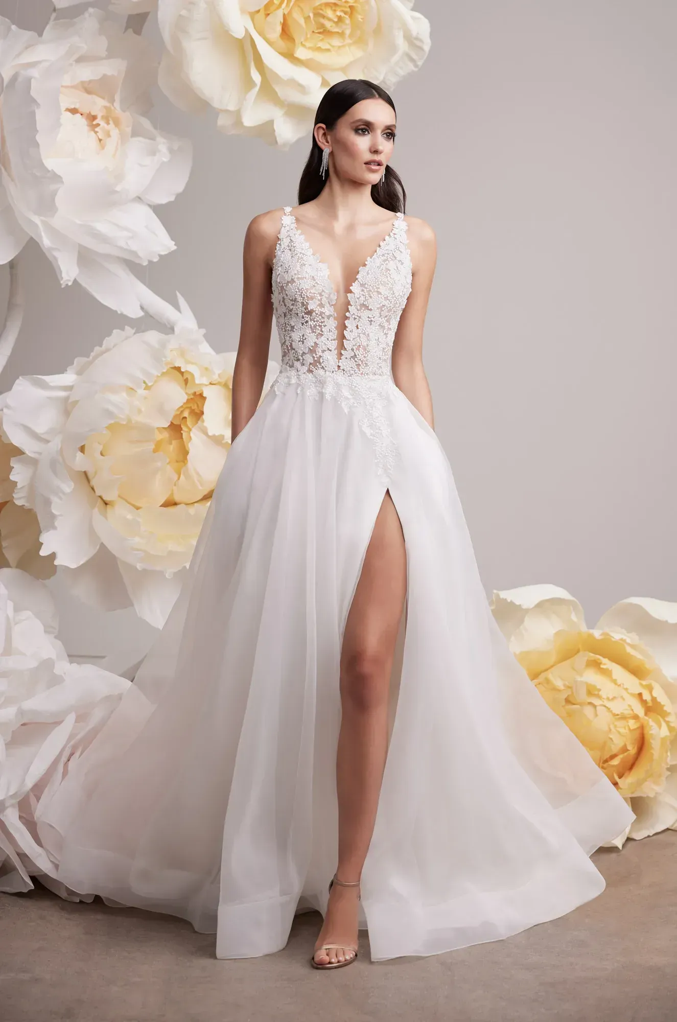 A woman is wearing a white wedding dress with a high slit. Mikaella 2453