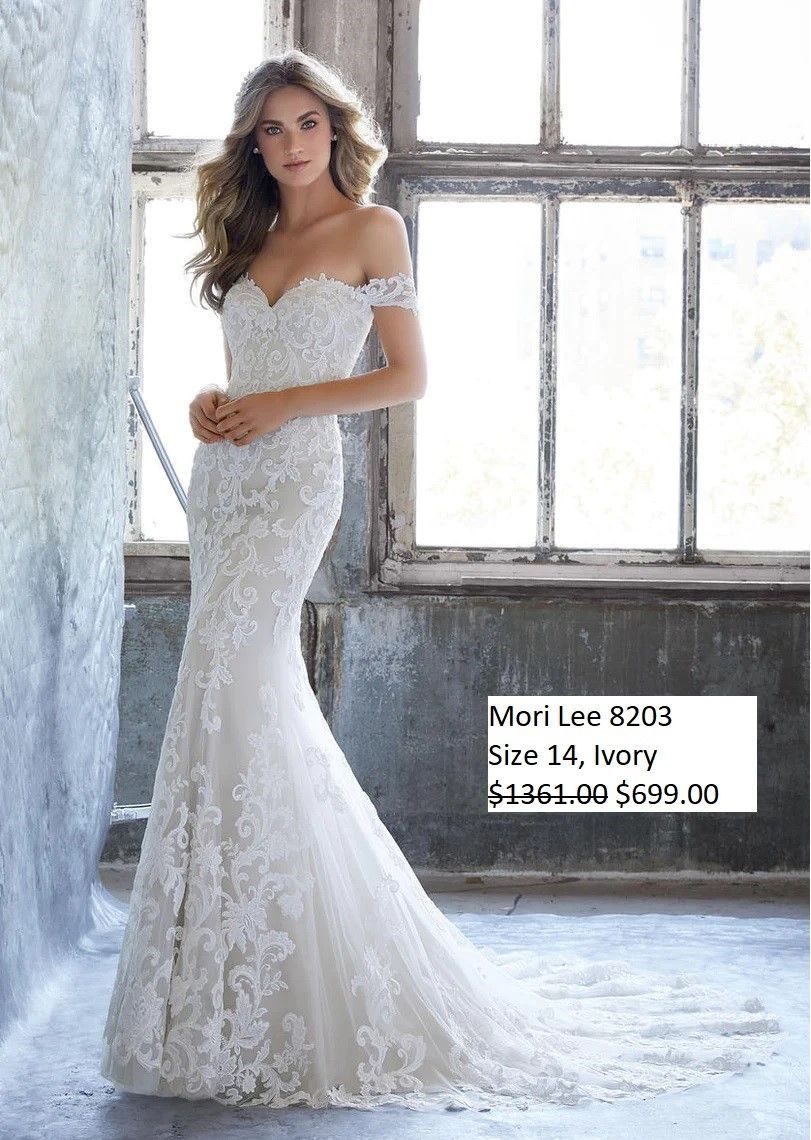 A woman in a white wedding dress is standing in front of a window.