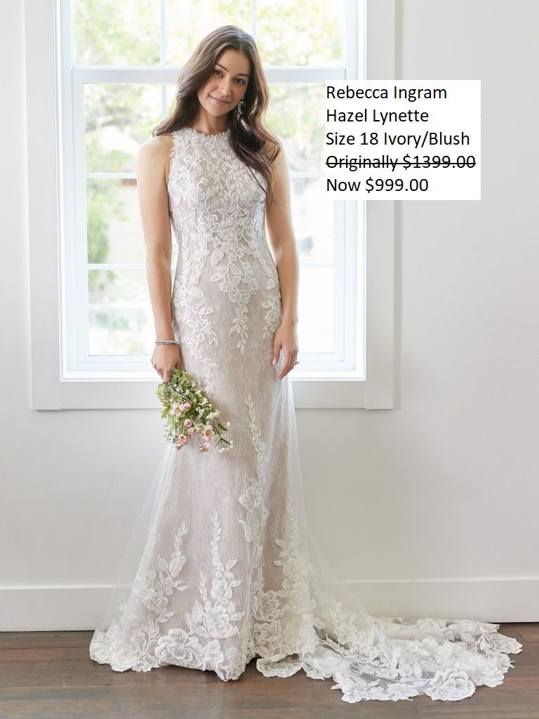 A woman in a wedding dress is standing in front of a window holding a bouquet of flowers.