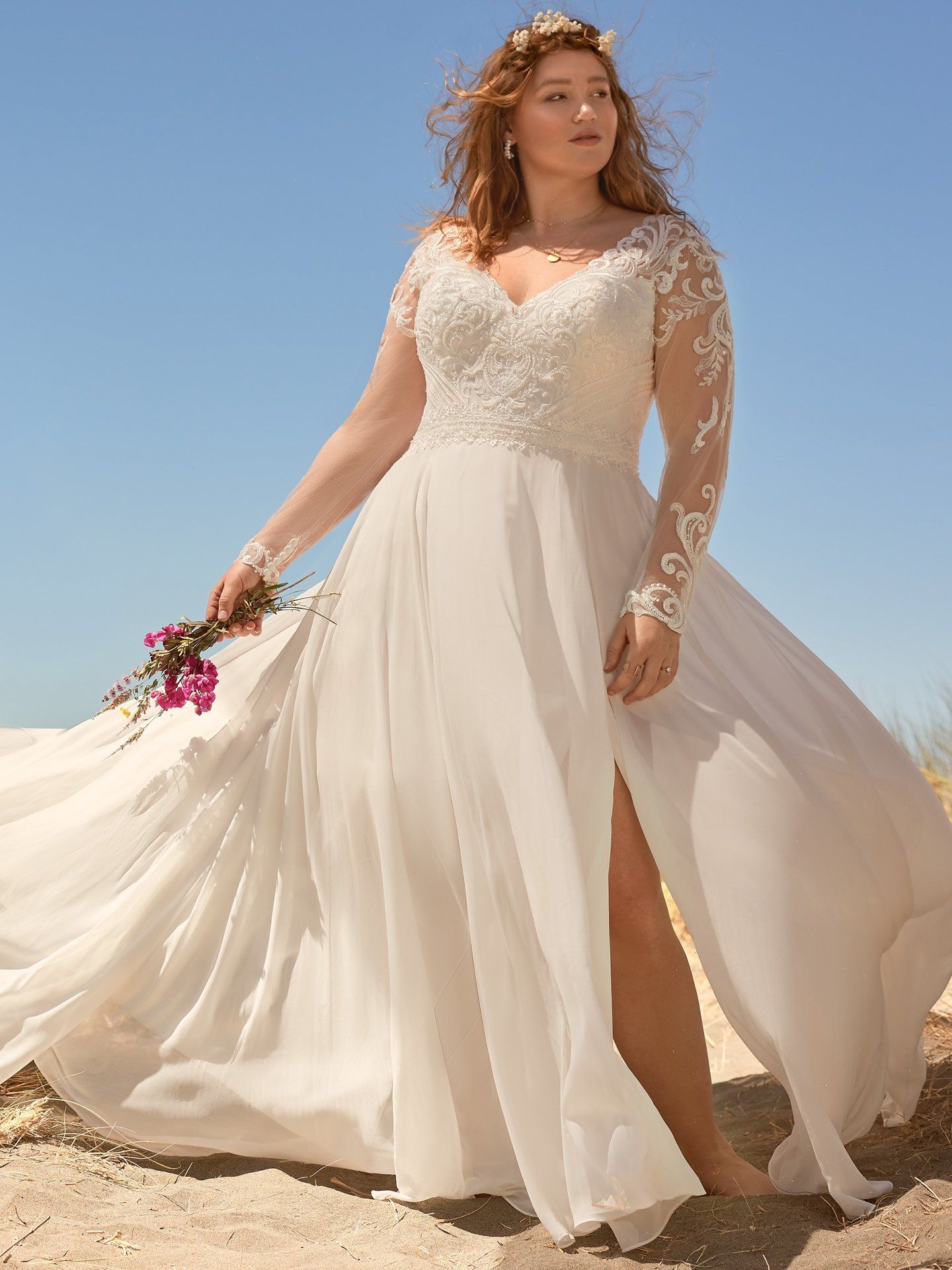 A plus size woman is wearing a white wedding dress and holding a bouquet of flowers.