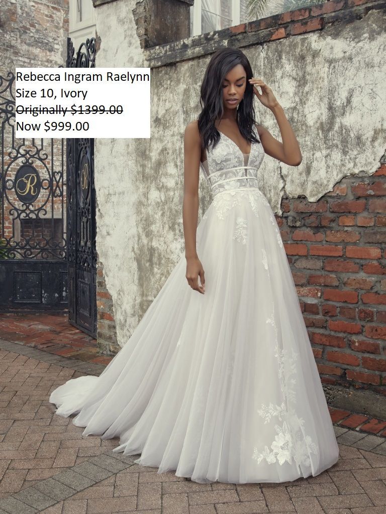 A woman in a white wedding dress is standing in front of a brick wall. Rebecca Ingram Raelynn