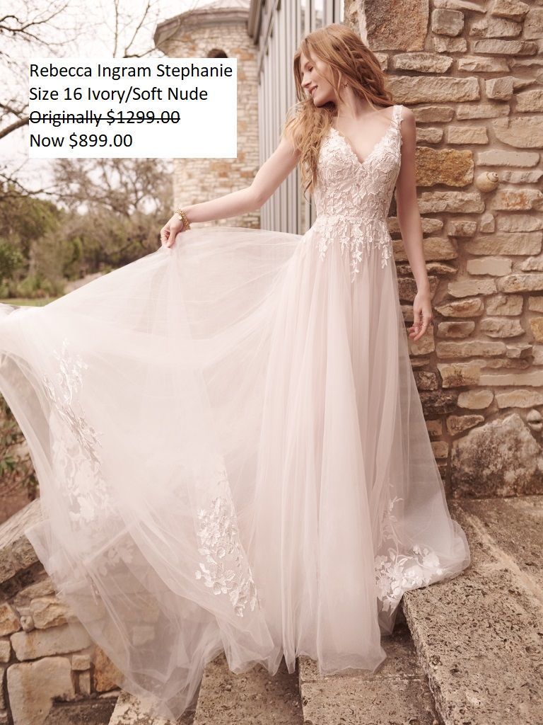 A woman in a wedding dress is standing in front of a stone wall.