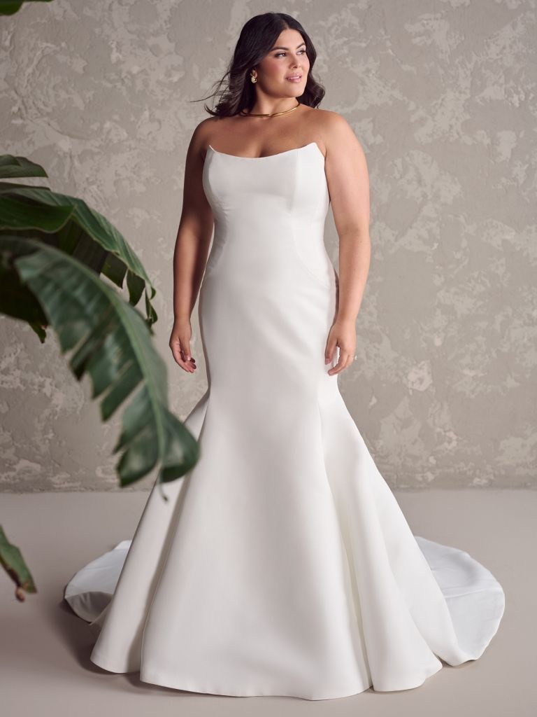 A plus size model is wearing a white wedding dress.