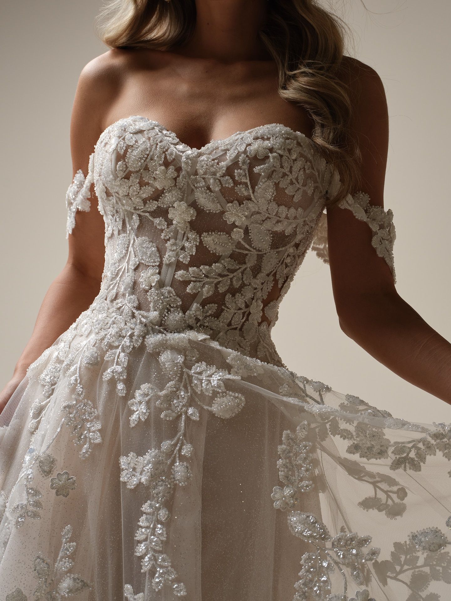 Woman in strapless, beaded, white wedding gown with floral embellishments.