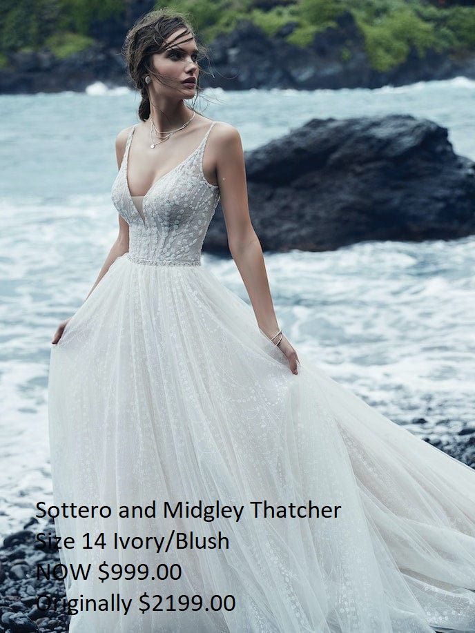 A woman in a wedding dress is standing on a rock near the ocean.