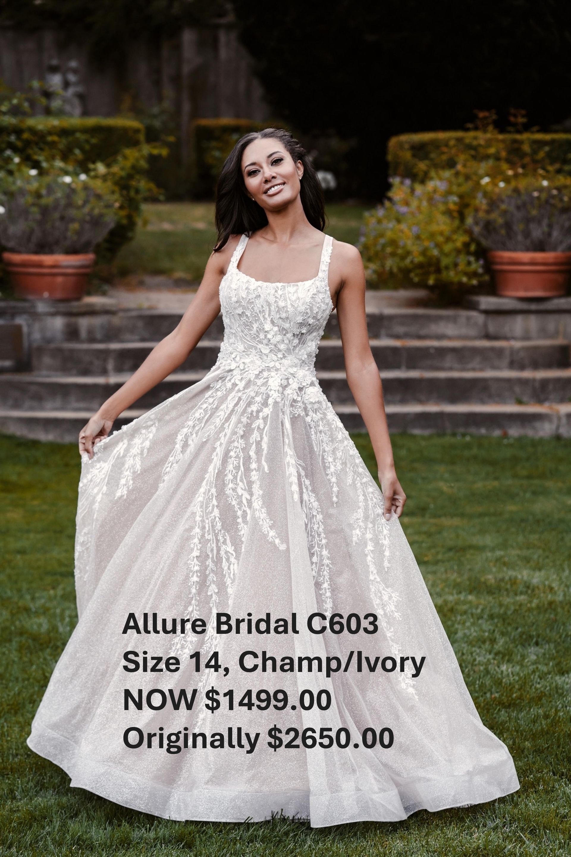 A woman in a white dress is standing in the grass. Allure Bridal C630