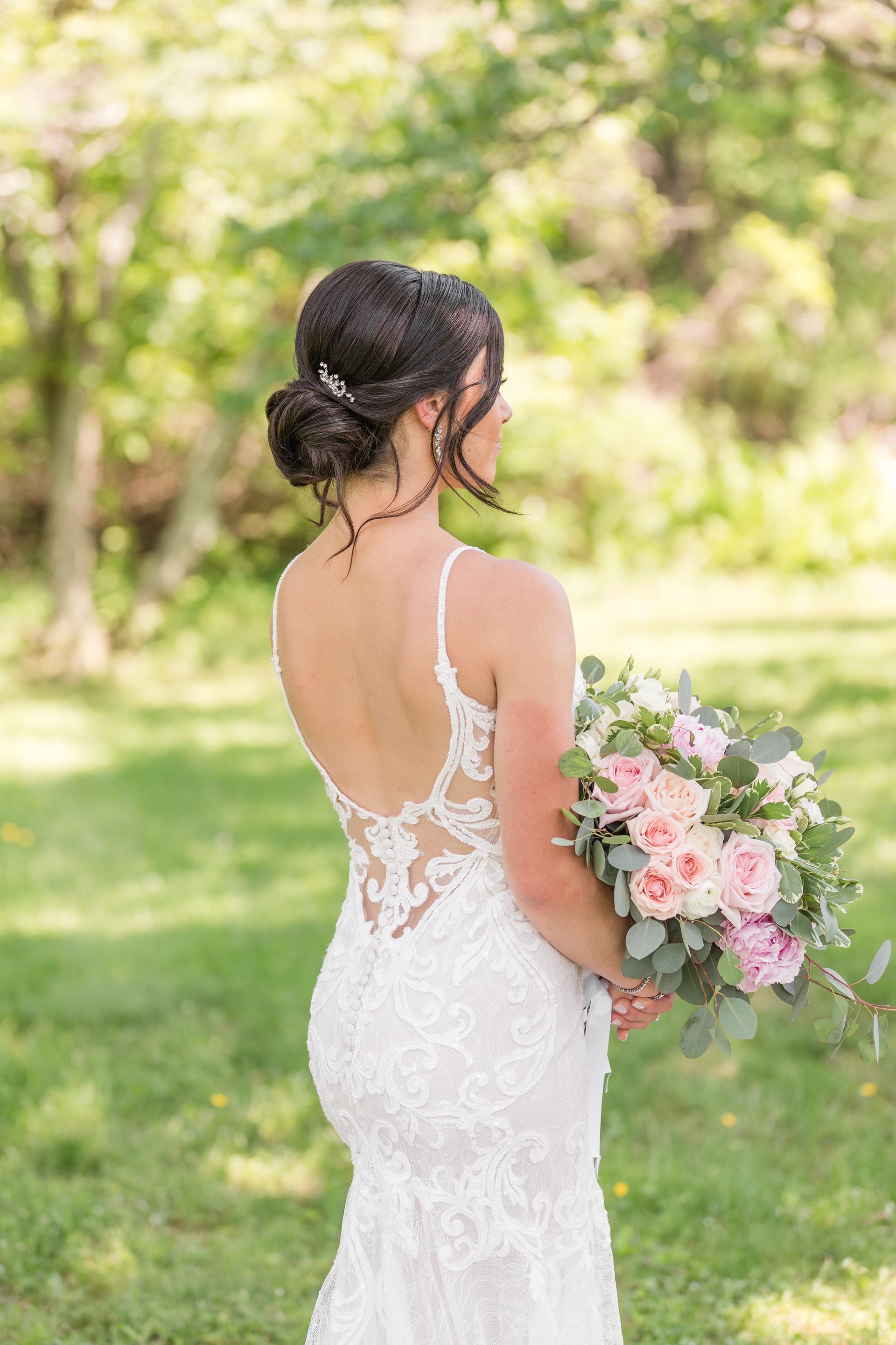 A bride in a lace wedding dress is holding a bouquet of flowers.