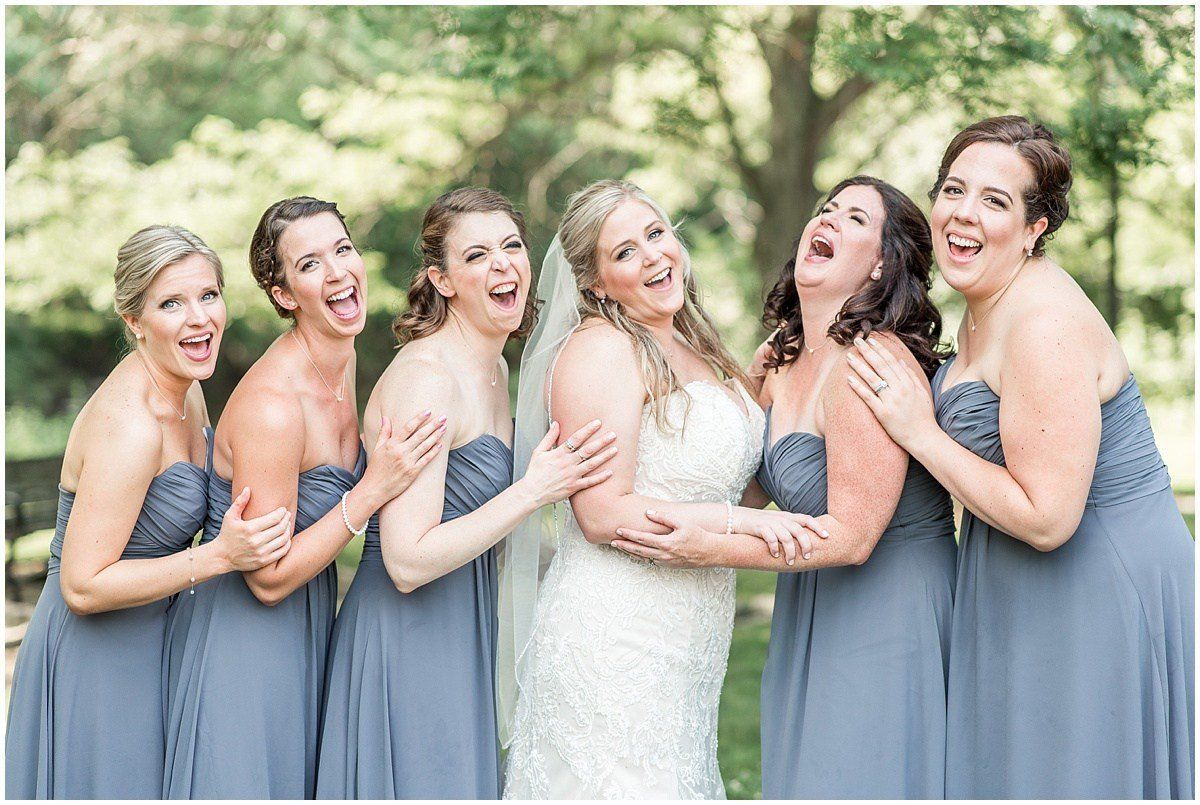 A bride and her bridesmaids are posing for a picture together and laughing.
