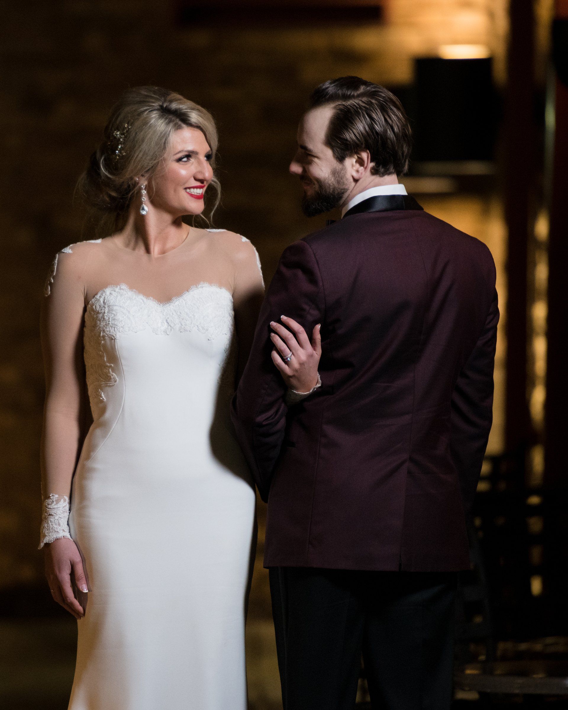 A bride and groom are standing next to each other and looking at each other.