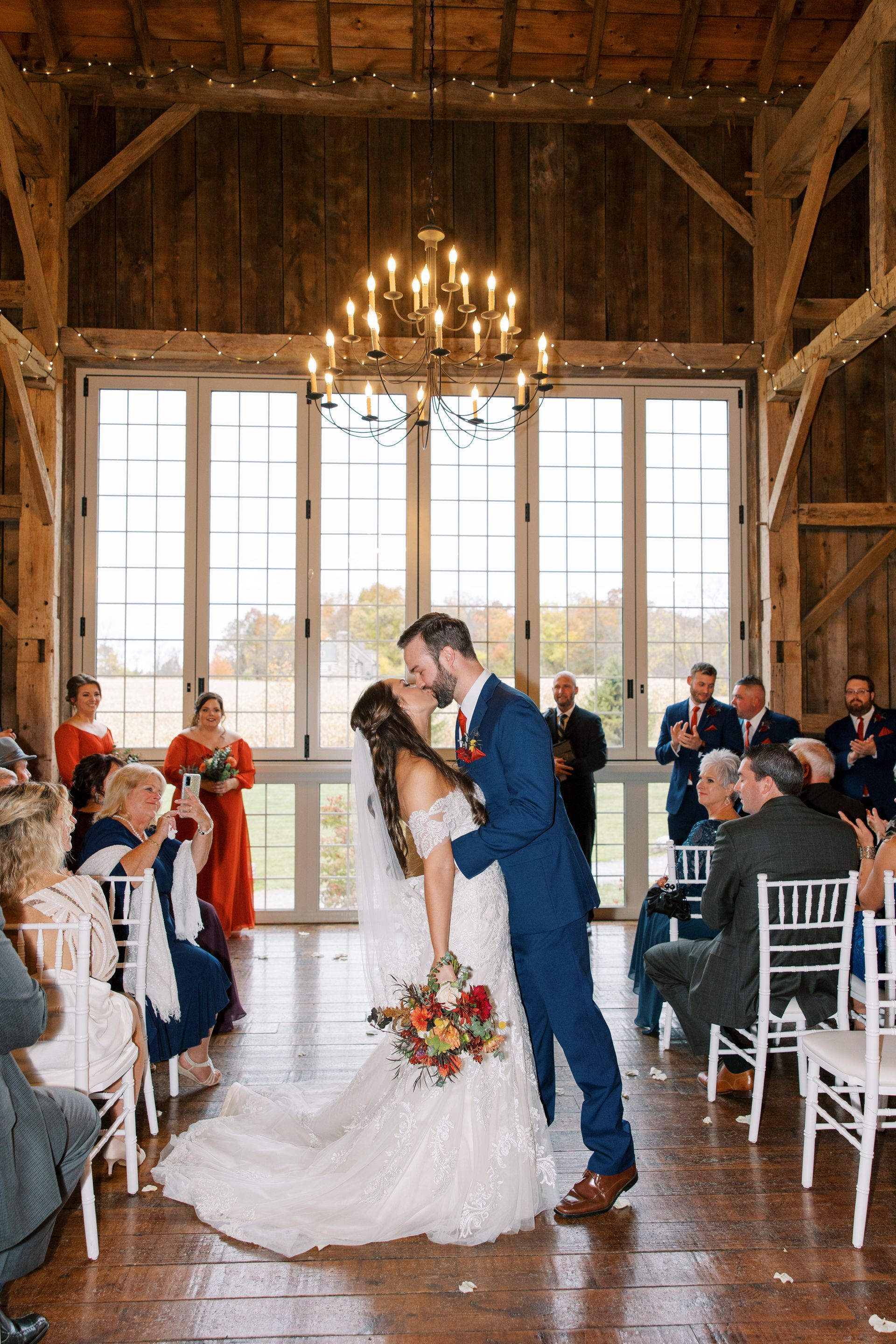 A bride and groom kissing at their wedding ceremony in a barn.