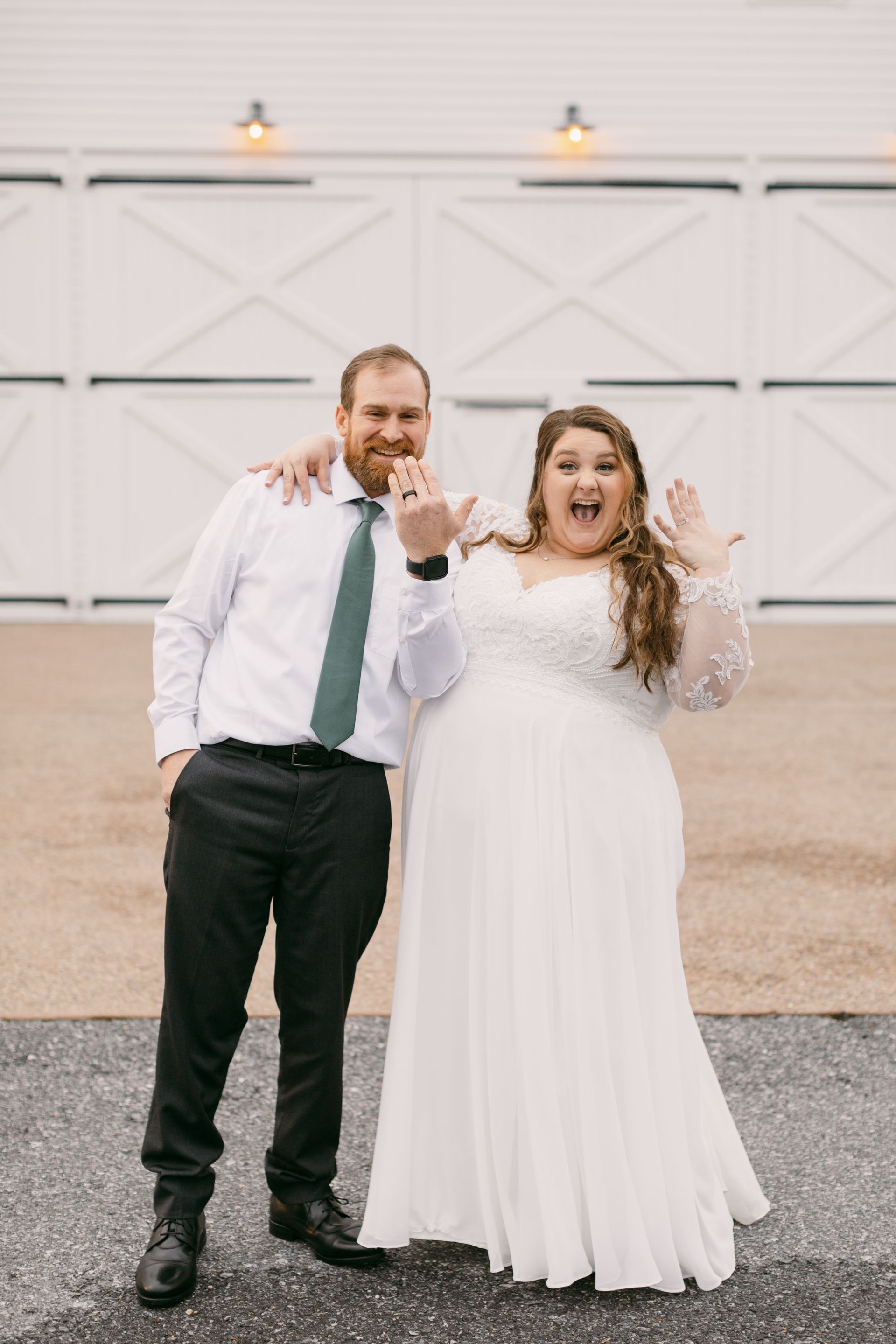 A bride and groom are posing for a picture in front of a white barn.