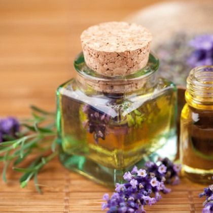 Small bottles of essential oil with lavender sprigs, cork stopper on a wooden surface.