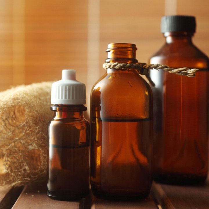 Amber glass bottles with oil, a loofah, on a wood surface.
