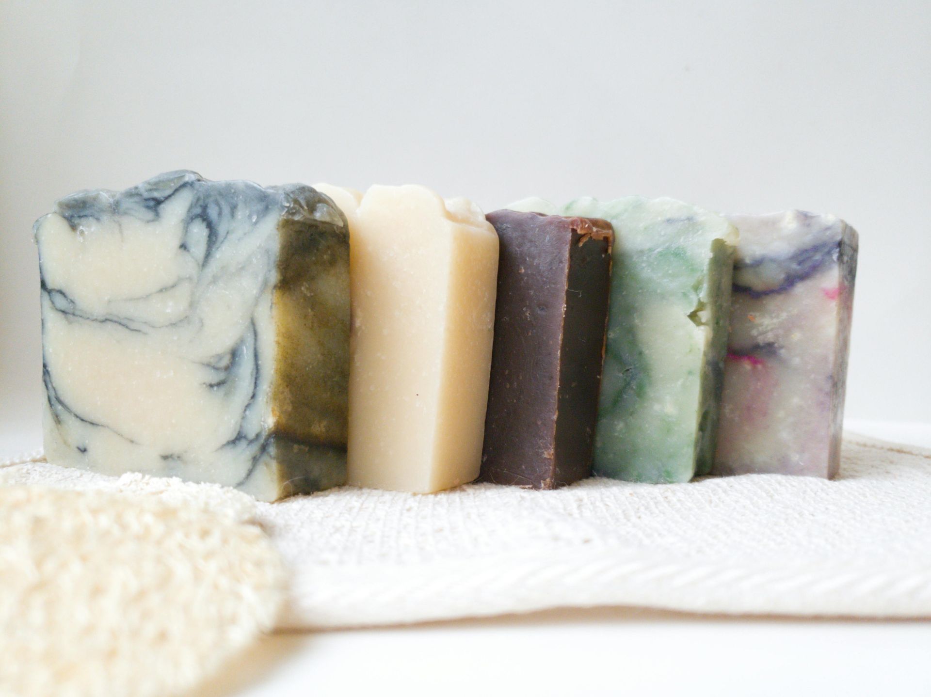 Variety of colorful handmade soap bars on a white towel.
