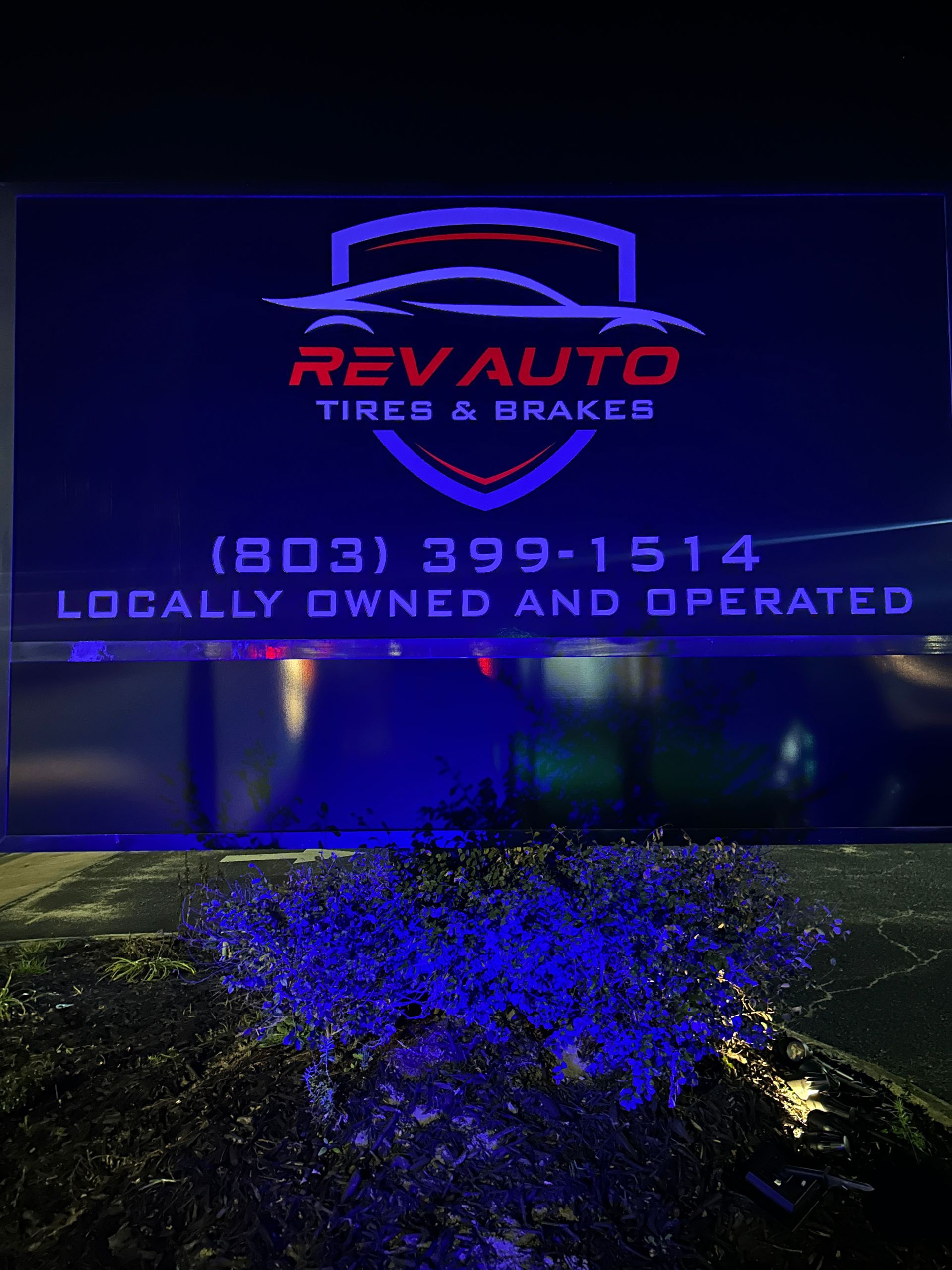 Sign for Rev Auto Tires & Brakes. Features logo, phone number, and 