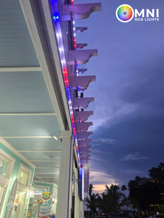 Building exterior with RGB LED lights illuminating the roof trim; blue and red lights against a dusk sky.