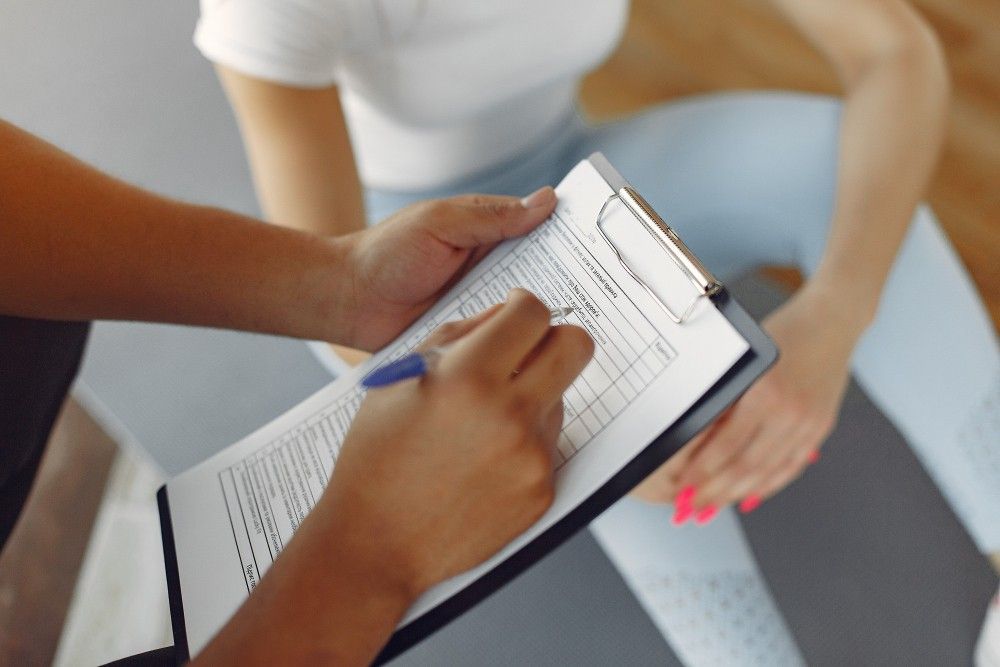 A person is writing on a clipboard with a pen.