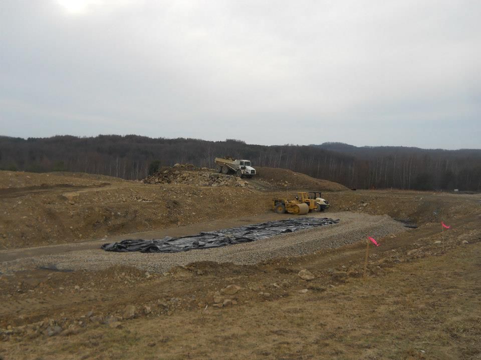 Construction site with a dump truck and a roller; a path laid with black fabric.