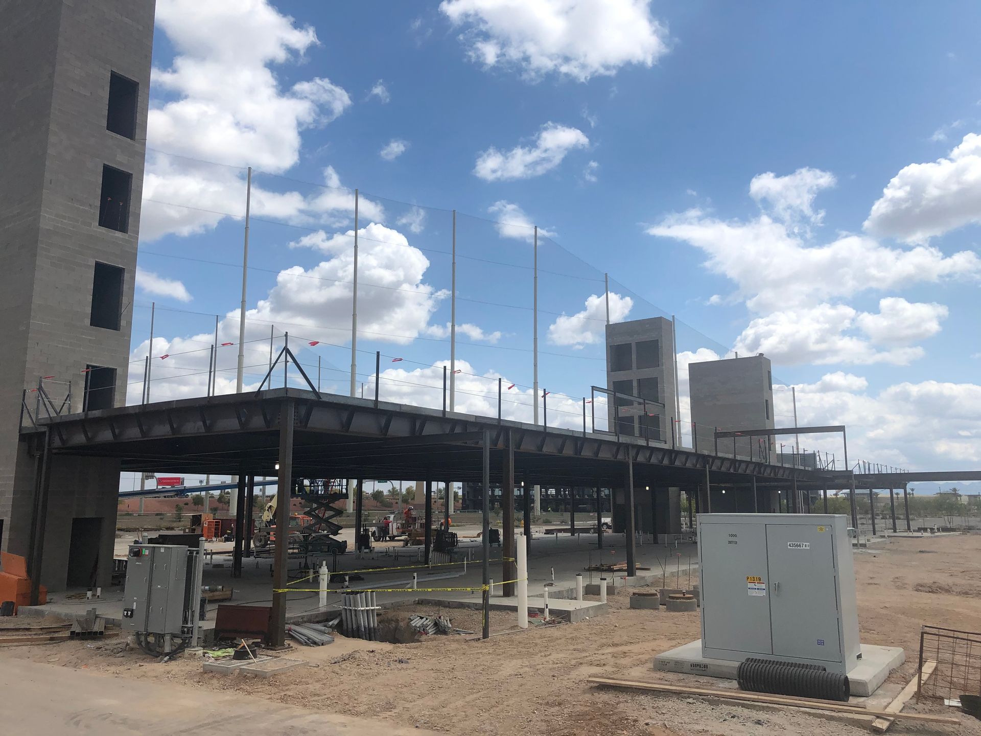 Construction site of a building under a cloudy sky. Steel beams and concrete columns form the structure.
