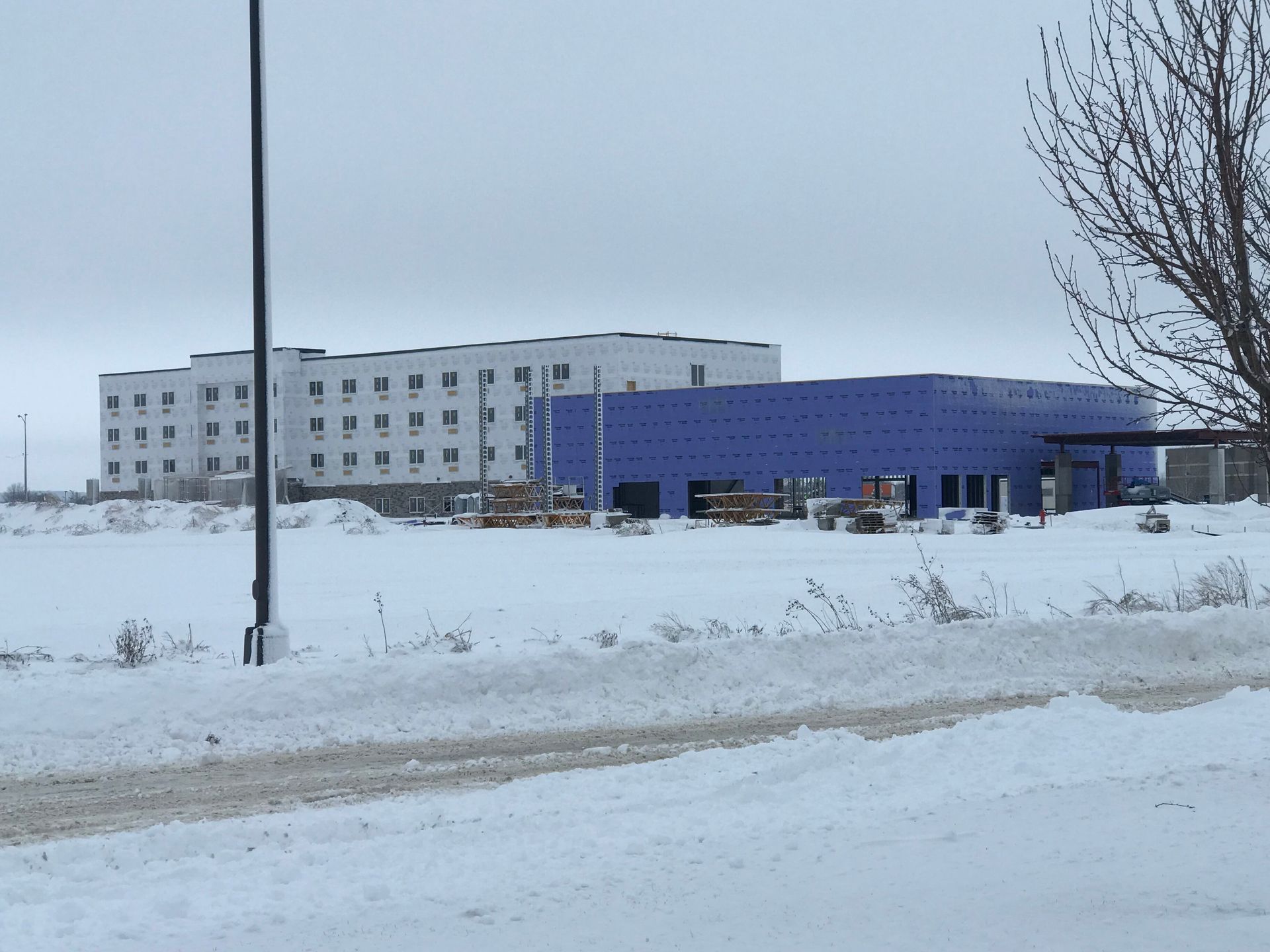 Snowy scene: multi-story white building and blue building under construction.