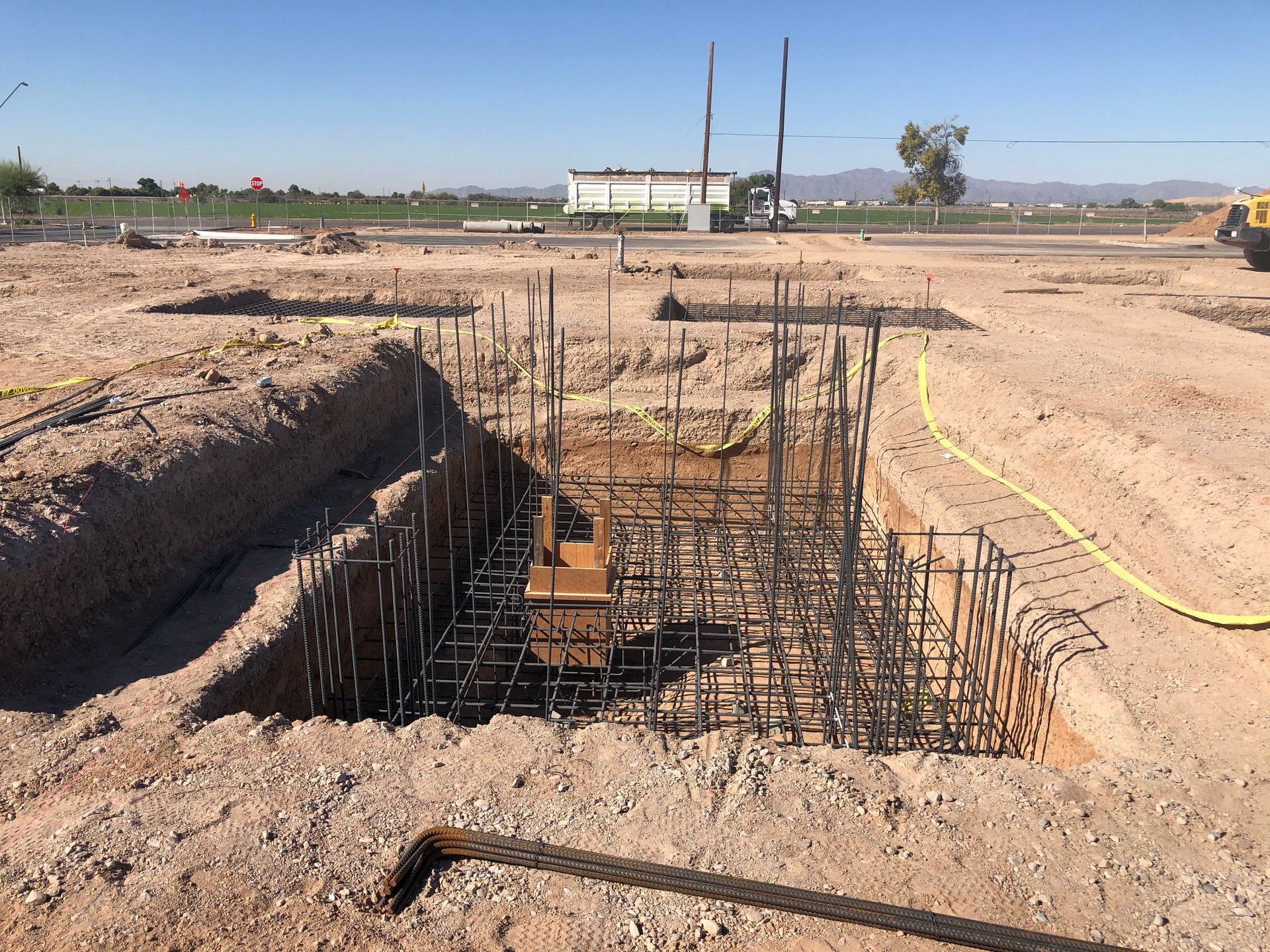 Construction site with exposed rebar, trenches, and prepared foundation.