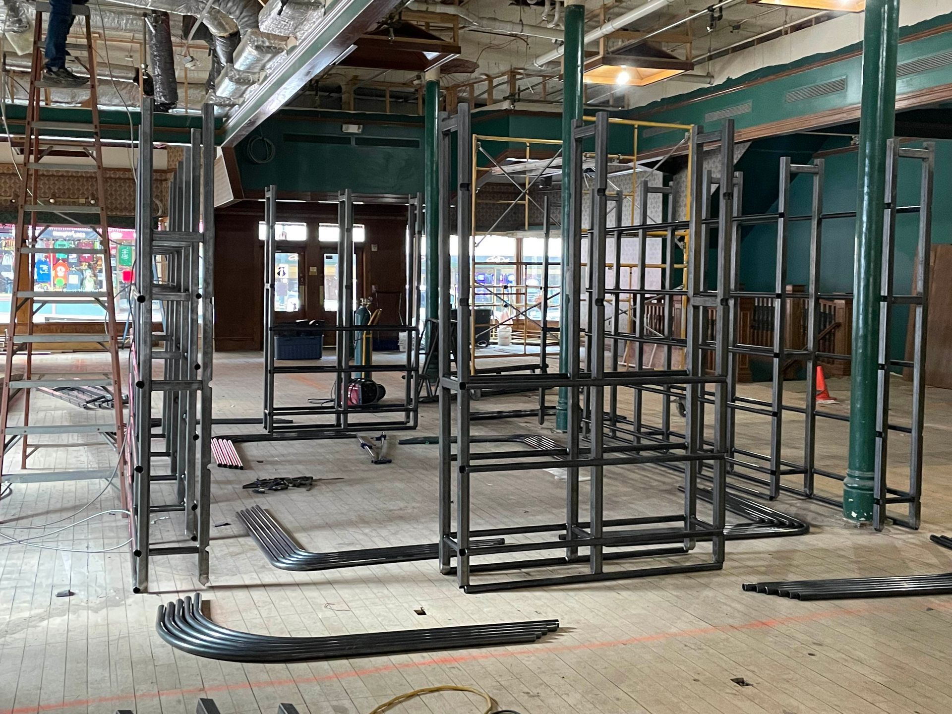 Construction site: metal framework of walls inside a building, tools and materials scattered on the floor.