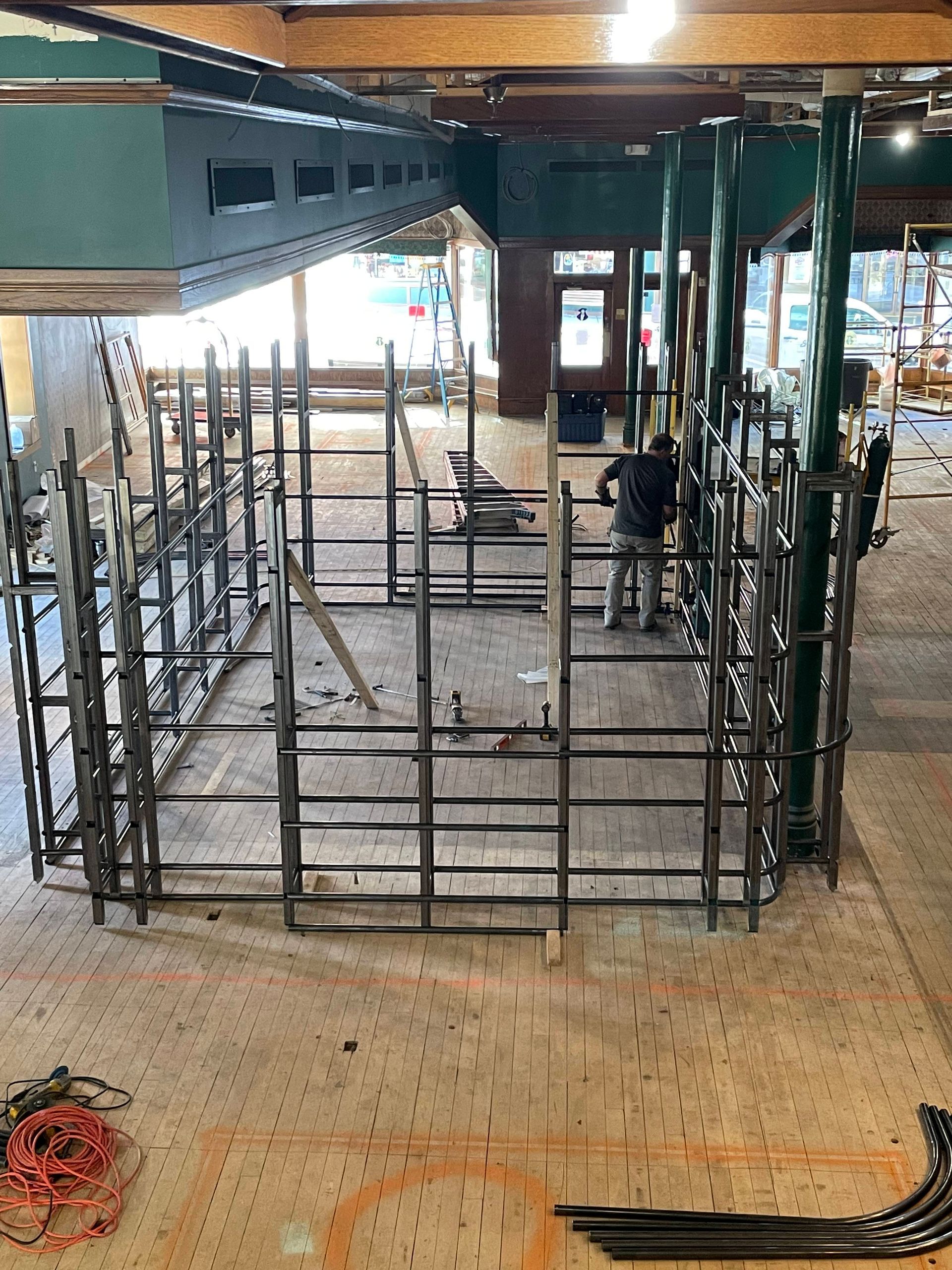Construction site with metal framework. A worker stands nearby.