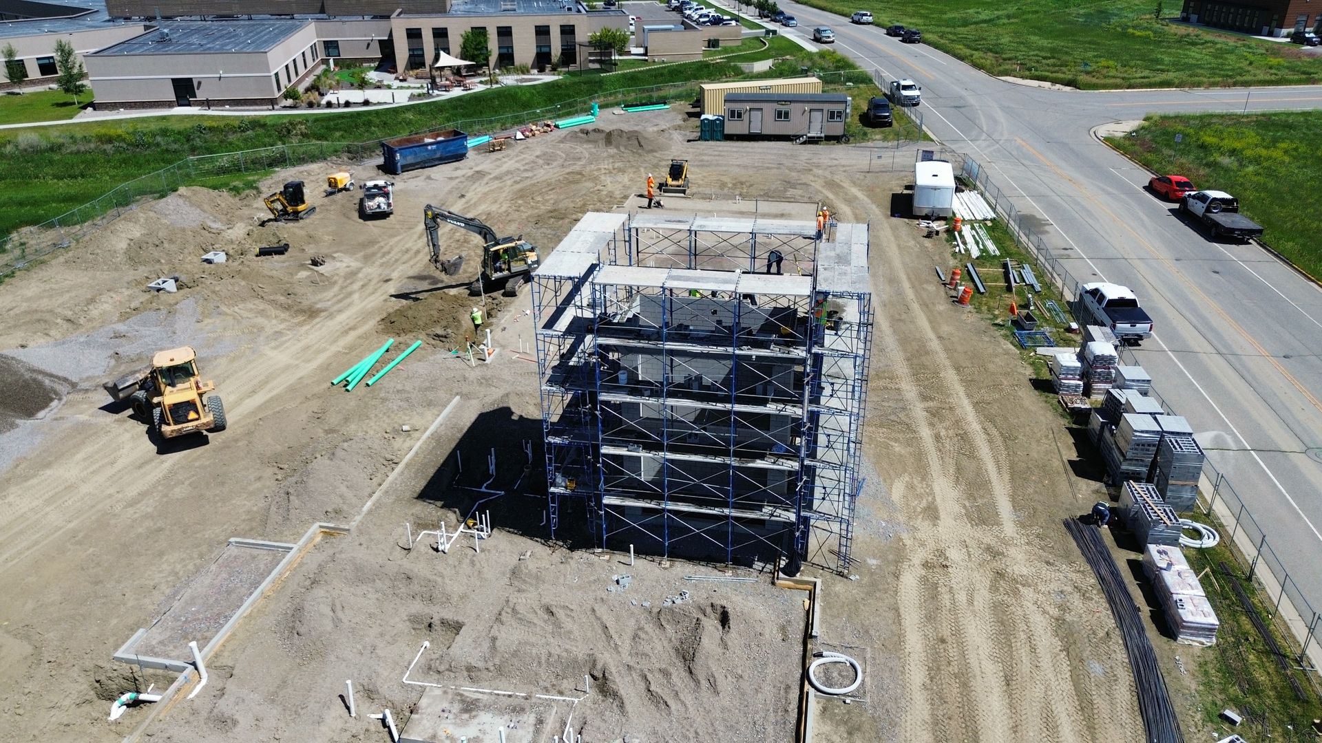 Construction site: partially built multi-story building surrounded by construction equipment and materials.