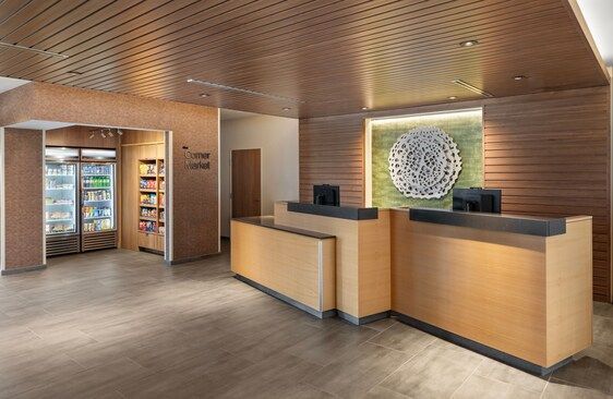 Hotel lobby with wooden paneling, reception desk, and a convenience store.