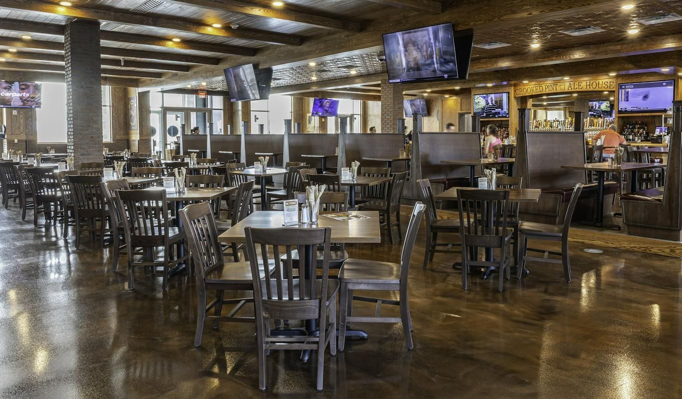Restaurant interior with tables and chairs, televisions, and a bar area.