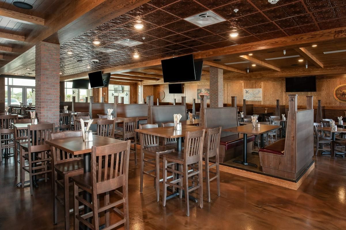Restaurant interior with wooden tables, chairs, booths, and televisions. Brown and tan color scheme.