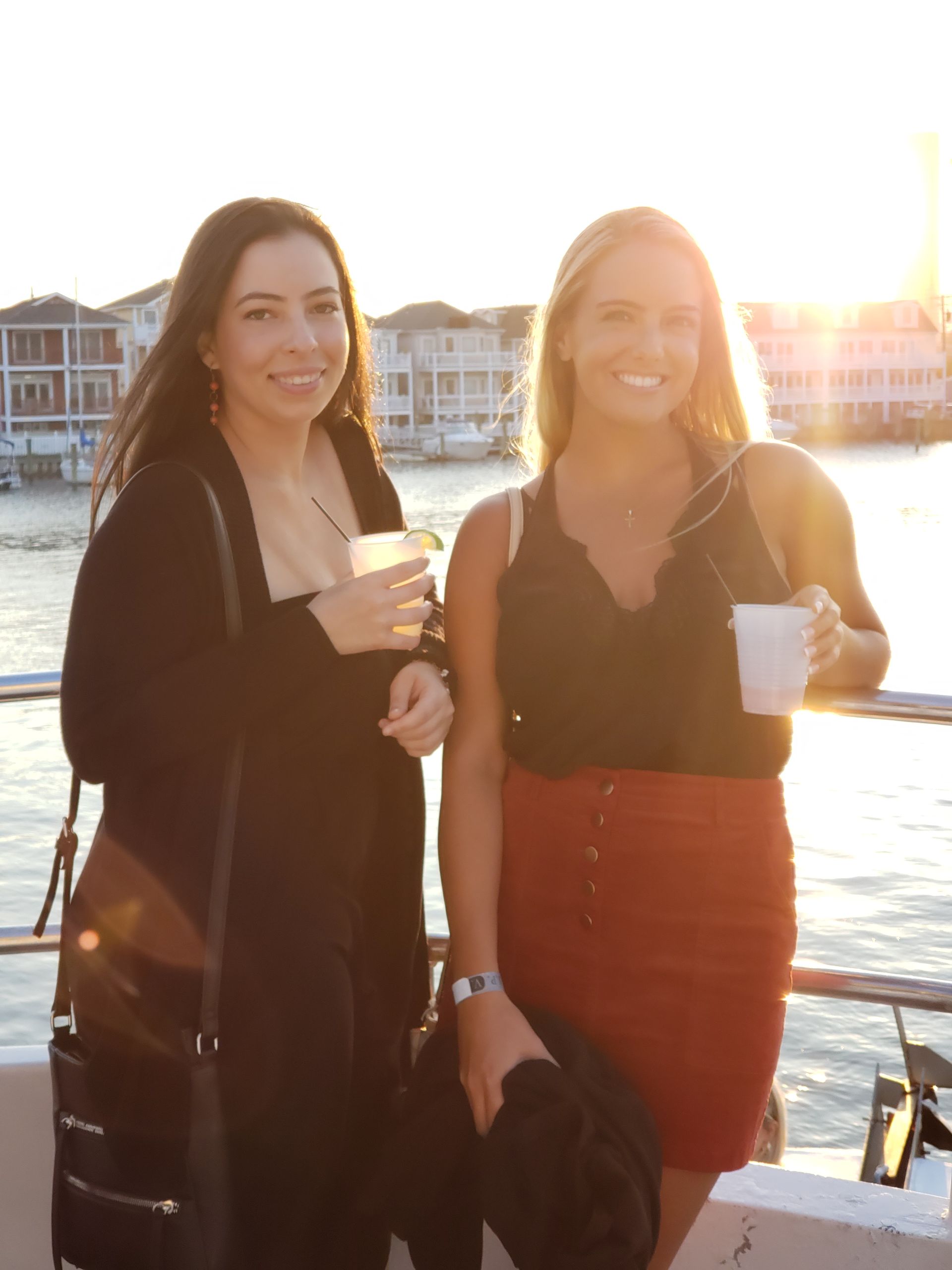 Teenagers at a party, hoisting a boy in an orange shirt into the air, celebrating.